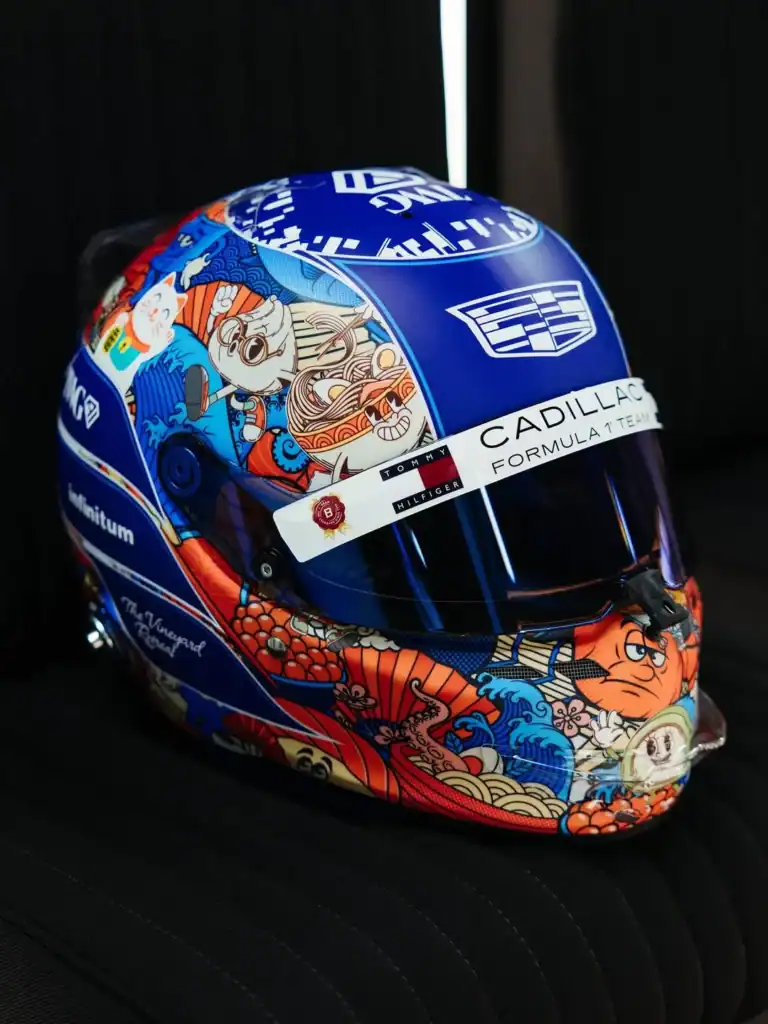 Valtteri Bottas Japanese GP 2026 special helmet by Tiffany Cromwell featuring kawaii Japanese motifs including maneki-neko, ramen bowl, and wave patterns on a blue base with Cadillac F1 branding