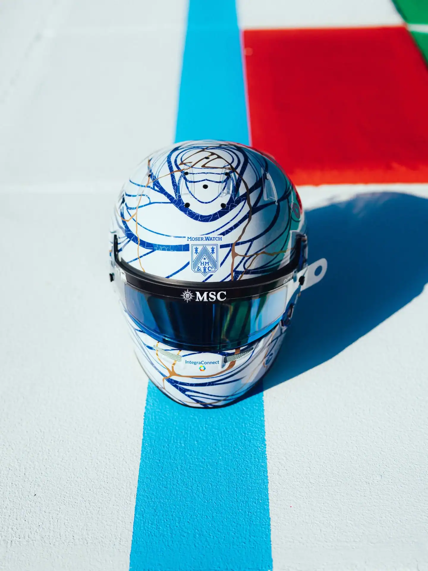 Pierre Gaslys Kintsugi-inspirierter Helm auf den Randsteinen von Suzuka &mdash; Frontansicht mit blauem Visier, wei&szlig;er Basis mit blauen Linien und goldenen Adern, MSC- und Alpine-Branding
