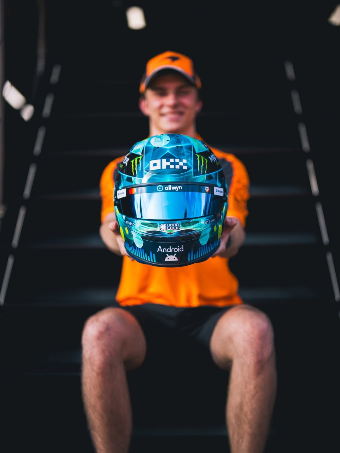 Oscar Piastri holds his 2026 Austrian GP helmet, the Allwyn sound-wave design, front view
