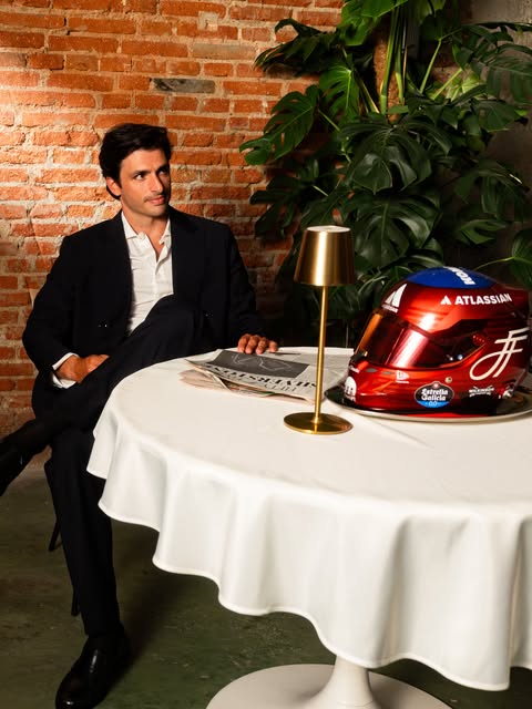 Carlos Sainz seated beside his special candy-red 2026 British GP helmet