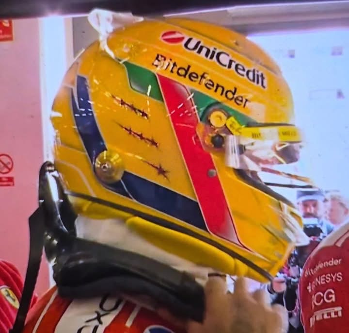 Side view of Lewis Hamilton's 2026 Silverstone helmet with the red star-cut stripe, green brow band and blue side band echoing his 2004 junior-era design