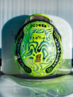 Lando Norris's fluoro-green 2026 British Grand Prix helmet covered in chrome liquid-metal blob swirls, with a Union Jack number badge.