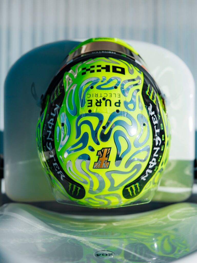 Lando Norris's fluoro-green 2026 British Grand Prix helmet covered in chrome liquid-metal blob swirls, with a Union Jack number badge.