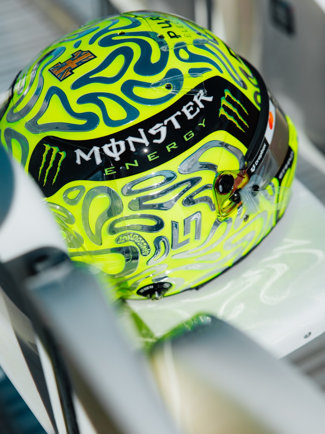 Rear view of Lando Norris's Silverstone helmet showing the chrome number and Monster Energy band over the fluoro-green base.