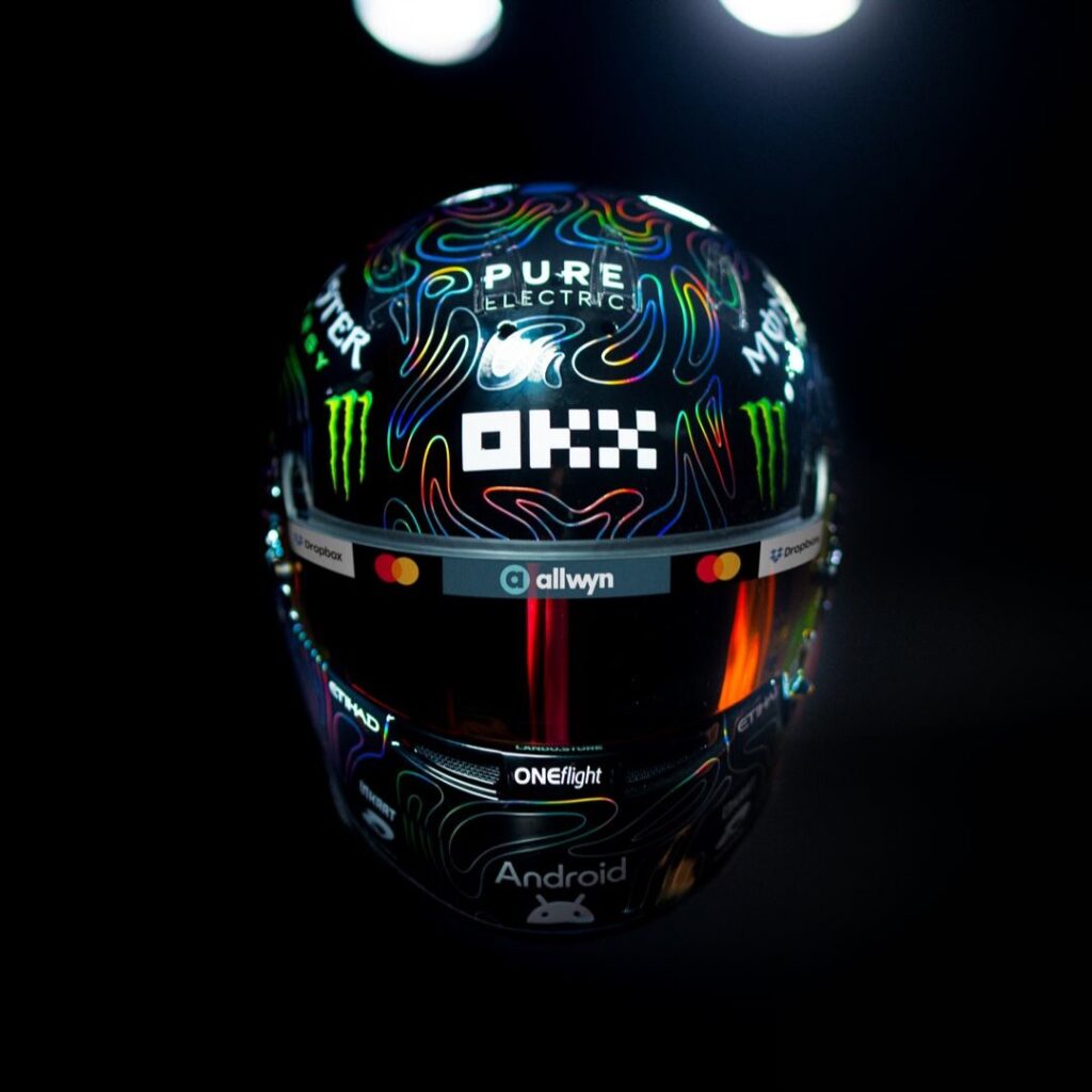 Lando Norris's 2026 Dutch GP helmet: gloss-black shell with holographic contour-line artwork and OKX branding on the crown