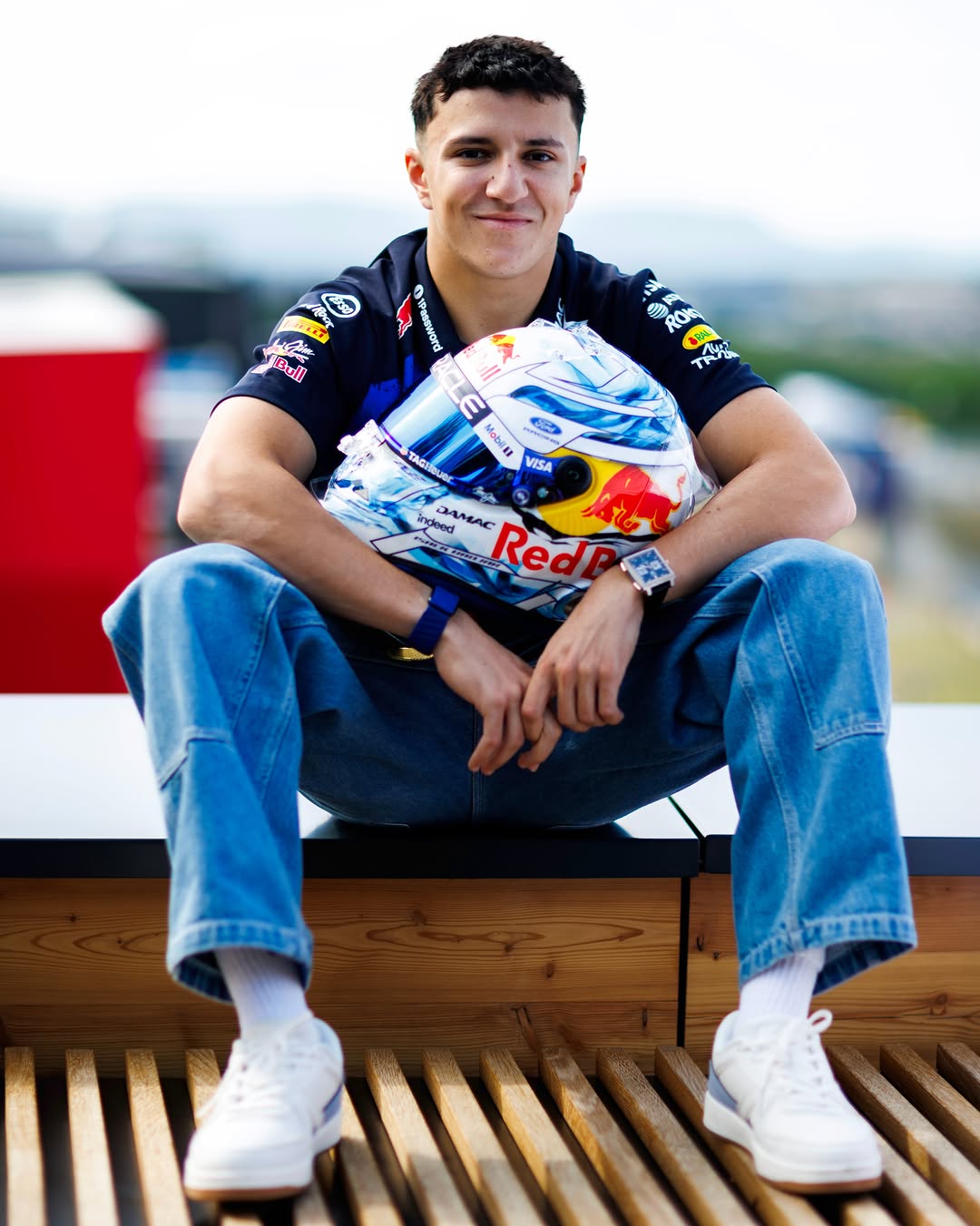 Isack Hadjar seated holding his 2026 Dutch Grand Prix helmet