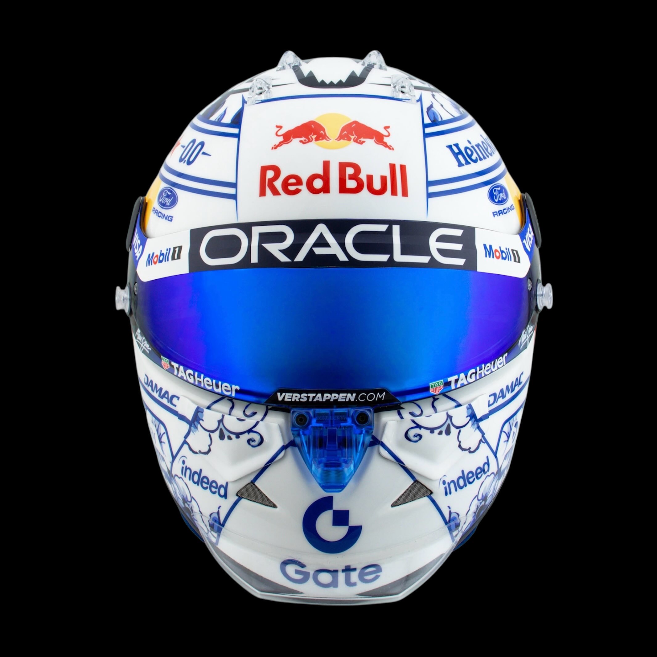 Front view of the helmet: blue mirrored visor under the Oracle strip, Delft blue florals across the chin bar.