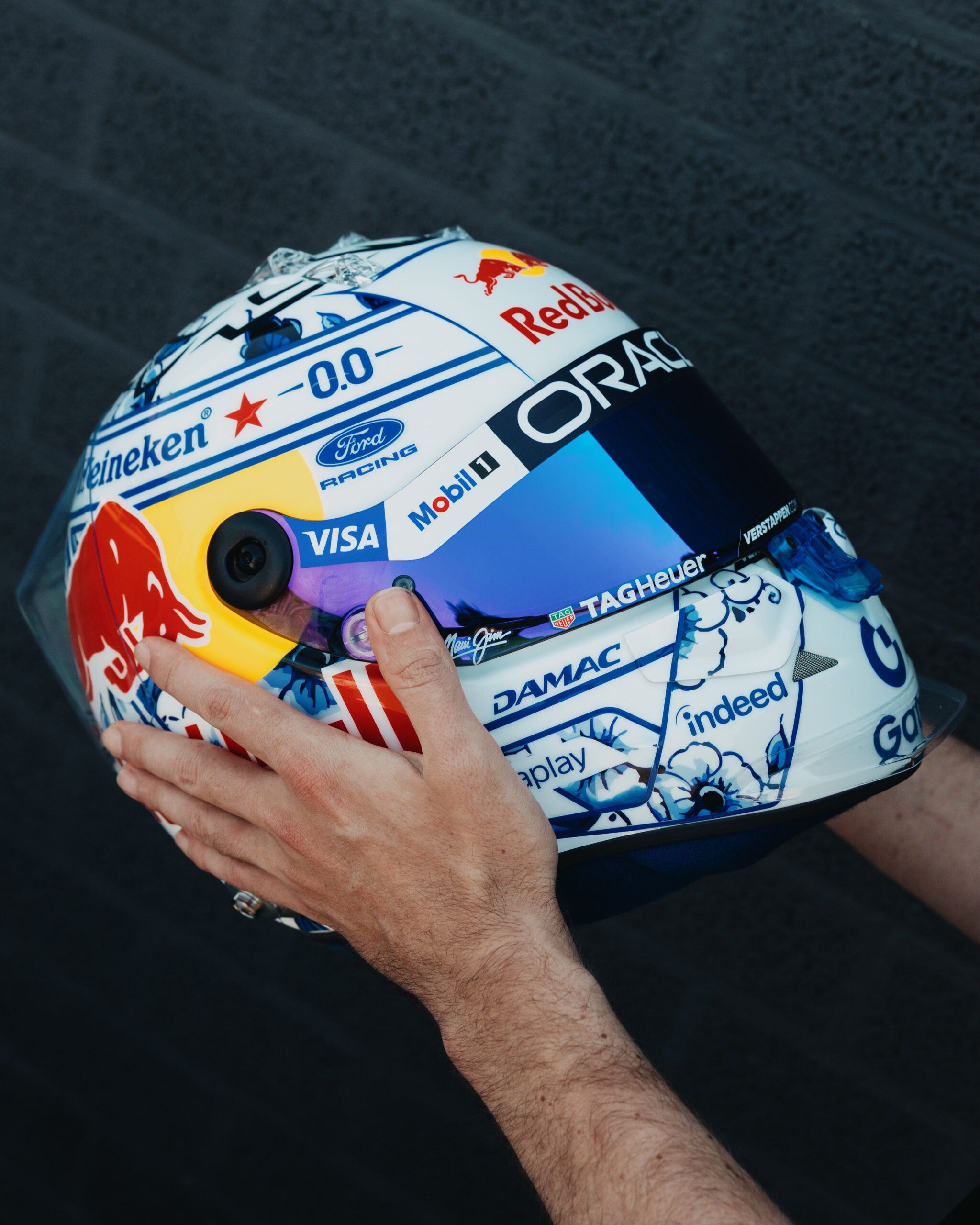 Rear three-quarter view of the helmet, the Heineken wordmark set in a Delft-style blue cartouche above the painted lower shell.