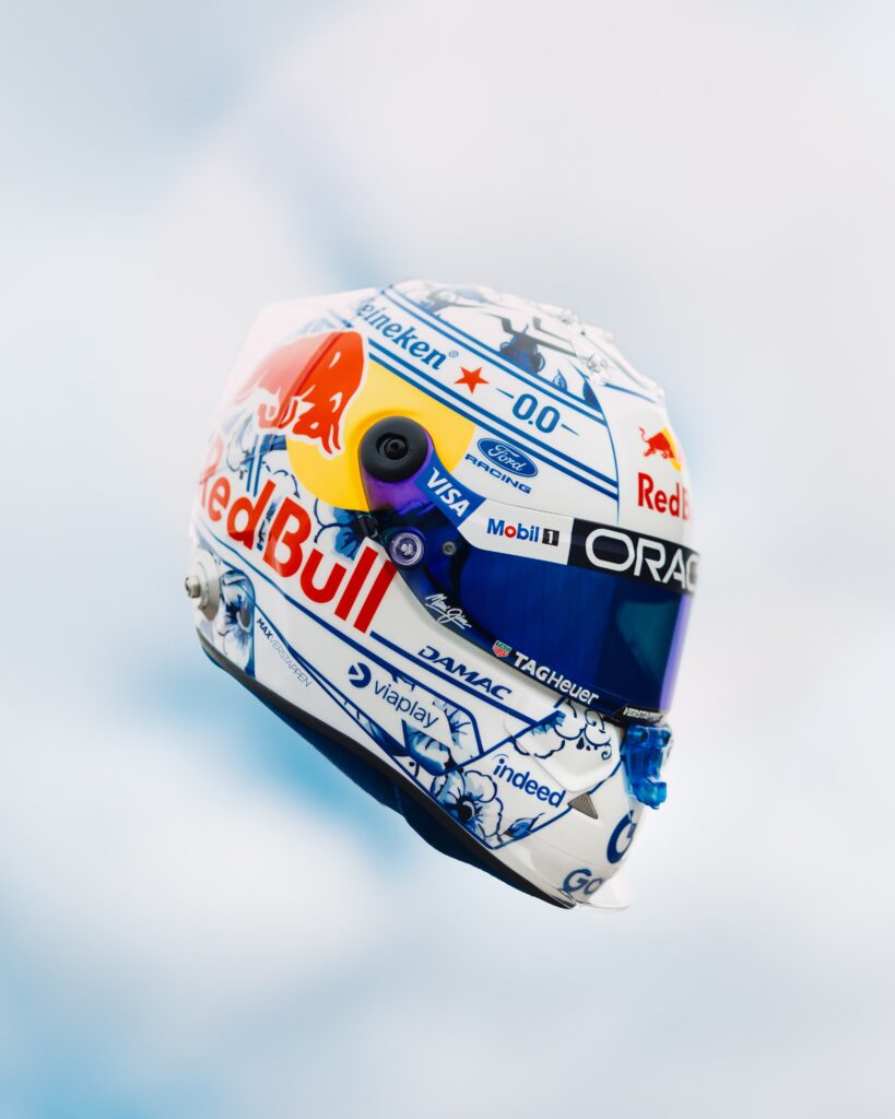 Three-quarter view of the white shell with cobalt Delft blue tulips and scrollwork, and a blue mirrored visor.
