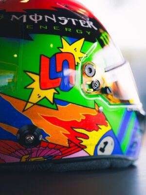 Side view of Lando Norris's 2026 Spanish GP helmet showing the red and blue LN monogram inside yellow comic starbursts