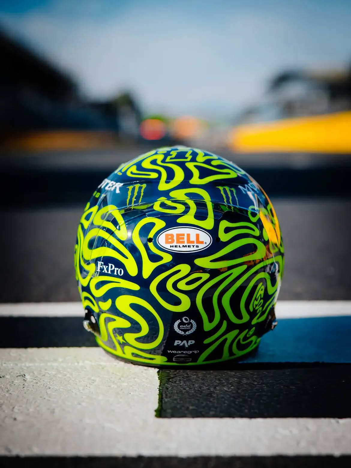 Casco de Lando Norris en Monza 2026: un tributo a Valentino Rossi en remolinos amarillo fluorescente sobre azul marino