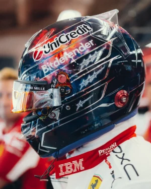 Lewis Hamilton's Austin 2026 helmet in profile: navy space scene with red and orange nebula, sketched white stars, chrome lines, gold mirrored visor