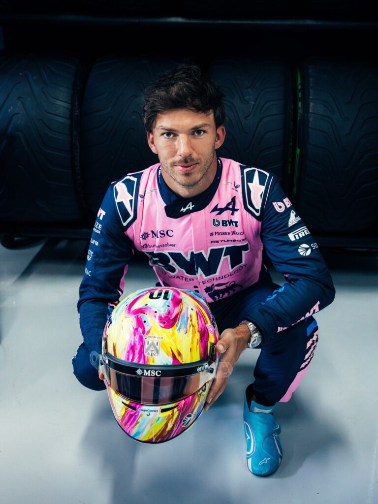 Pierre Gasly holding his special helmet for the 2026 Mexico City Grand Prix, covered in multicolour brushstrokes, MSC on the visor strip