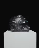 Fernando Alonso's 2026 Spanish GP helmet displayed on a white plinth, matte black with white pattern lines