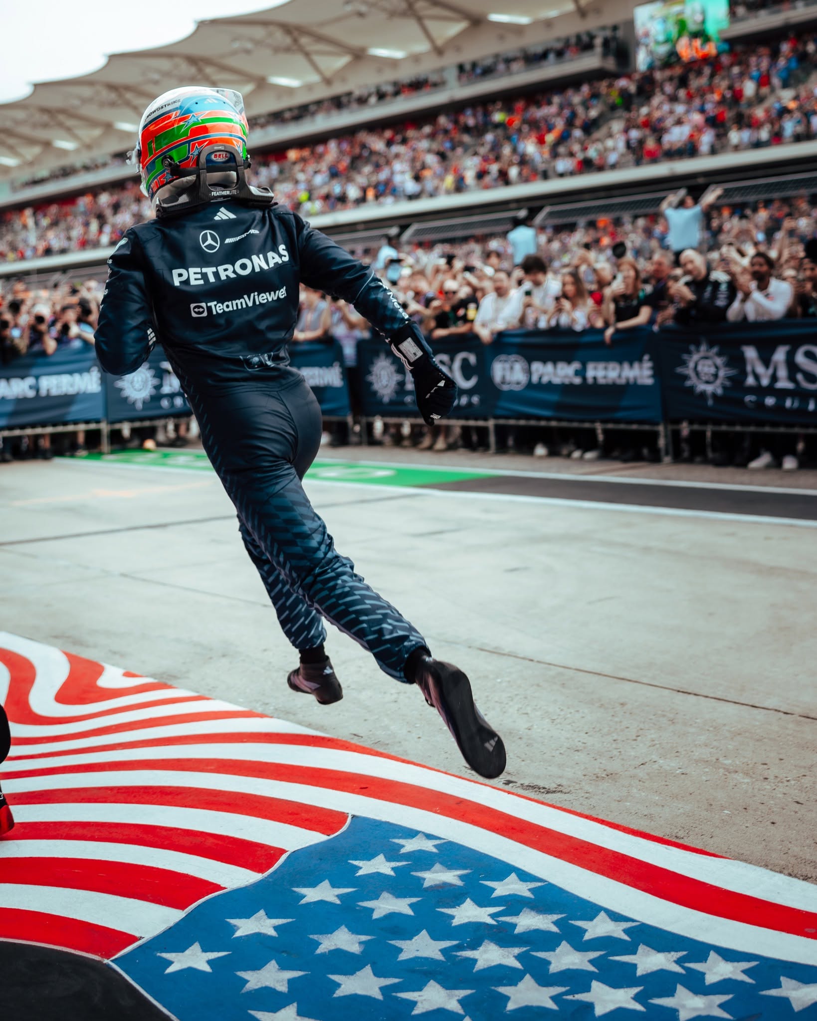 Kimi Antonelli runs across the stars-and-stripes carpet in parc fermé after his Austin win