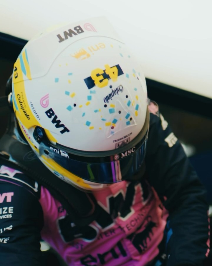 Franco Colapinto wearing his Austin 2026 helmet, seen from above, in his pink and navy Alpine race suit