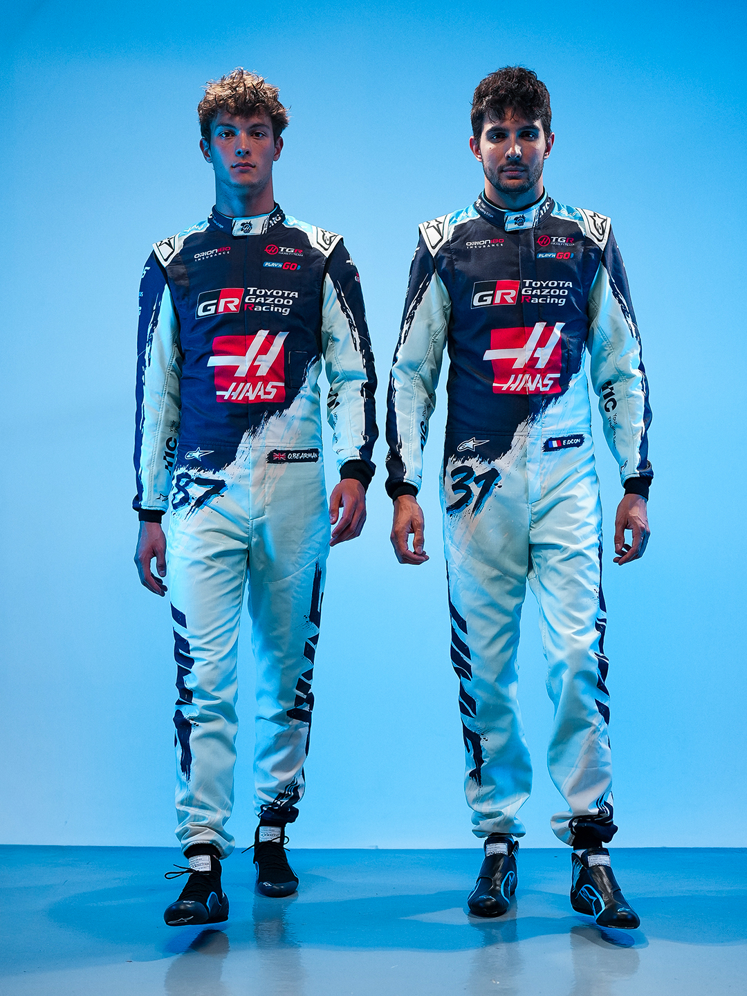 Oliver Bearman (87) and Esteban Ocon (31) in Haas's Austin race suits with brush-stroke legs