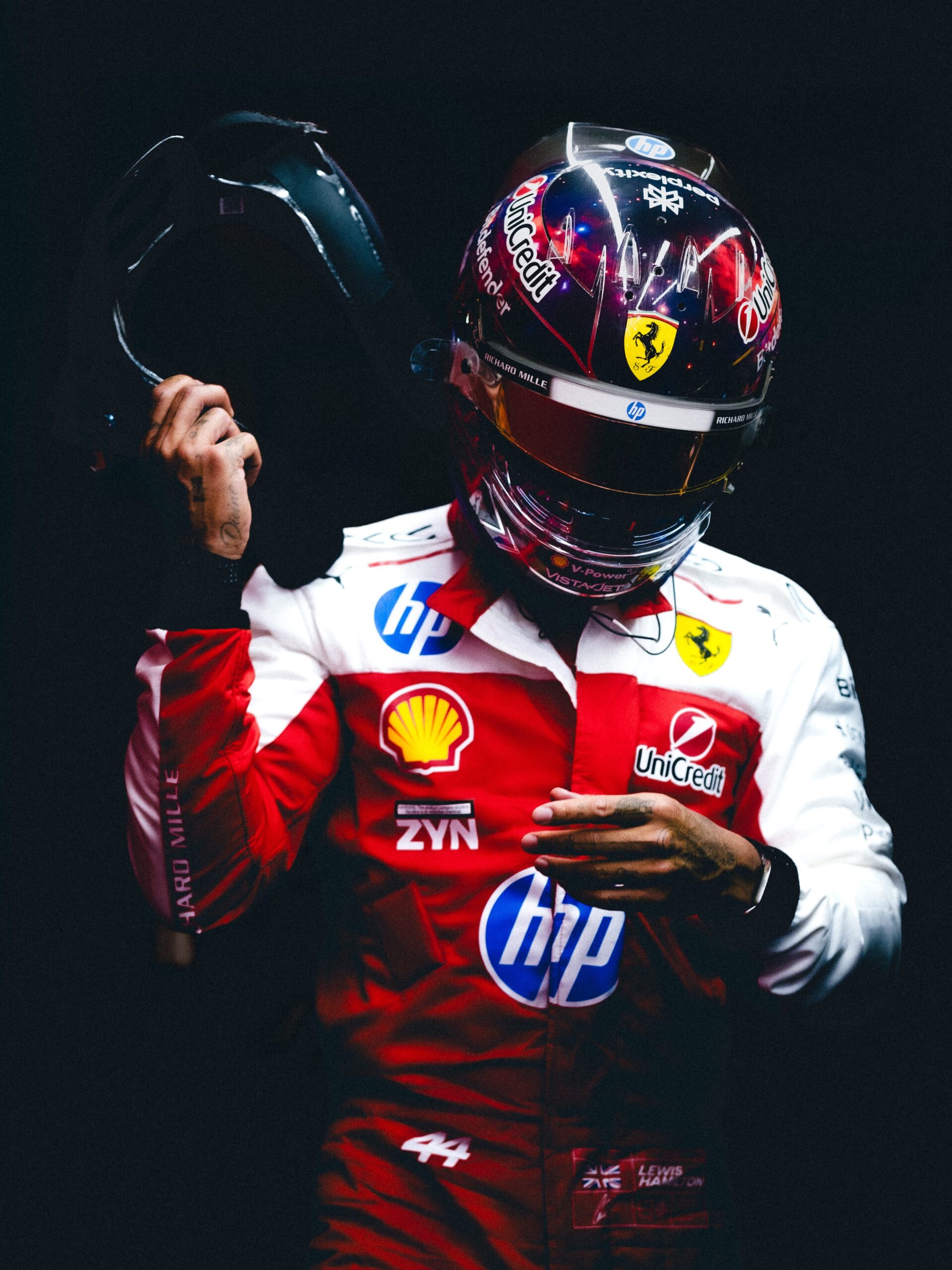 Lewis Hamilton in the garage in his Ferrari race suit, wearing his Austin 2026 helmet, seen from the front