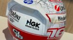 Back of Charles Leclerc's Austin 2026 helmet: Peroni Nastro Azzurro 0.0%, NGK Spark Plugs, CL16 logo and number 16 over the street map