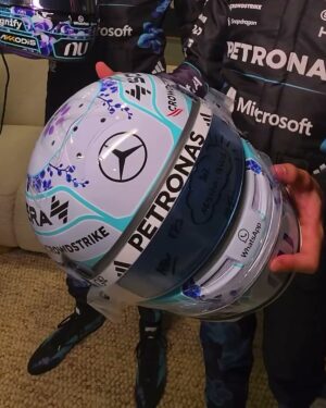 Front view of Kimi Antonelli's 2026 Singapore GP helmet, white base with blue-violet orchids, the Mercedes star and PETRONAS visor strip