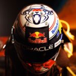 Front and top of Max Verstappen's white 2026 US GP Austin helmet: a navy cat-like face in a cowboy hat and a denim-look Red Bull brow panel